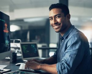 Man looking at the camera smiling while working on a computer