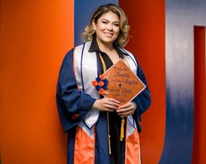 Elsa Trejo wearing graduation regalia and holding her grad cap