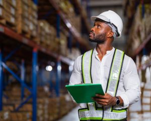 Man walking in a warehouse carrying a clipboard