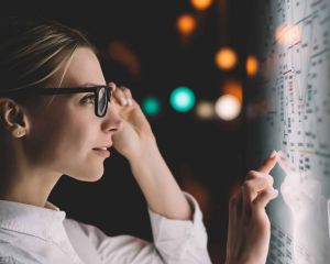 Woman touching her glasses and looking at a board