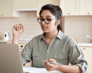 Woman talking in a meeting while on the computer