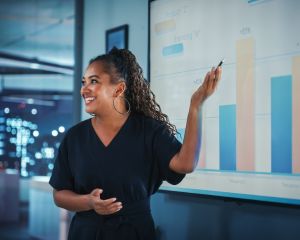 Woman smiling while presenting a chart on a whiteboard 